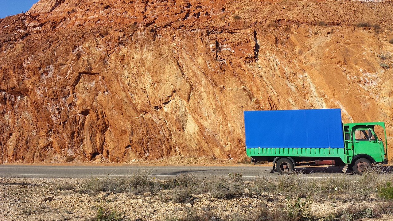 A blue and green lorry drives past a mine