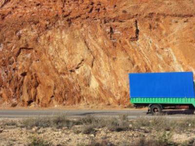 A blue and green lorry drives past a mine